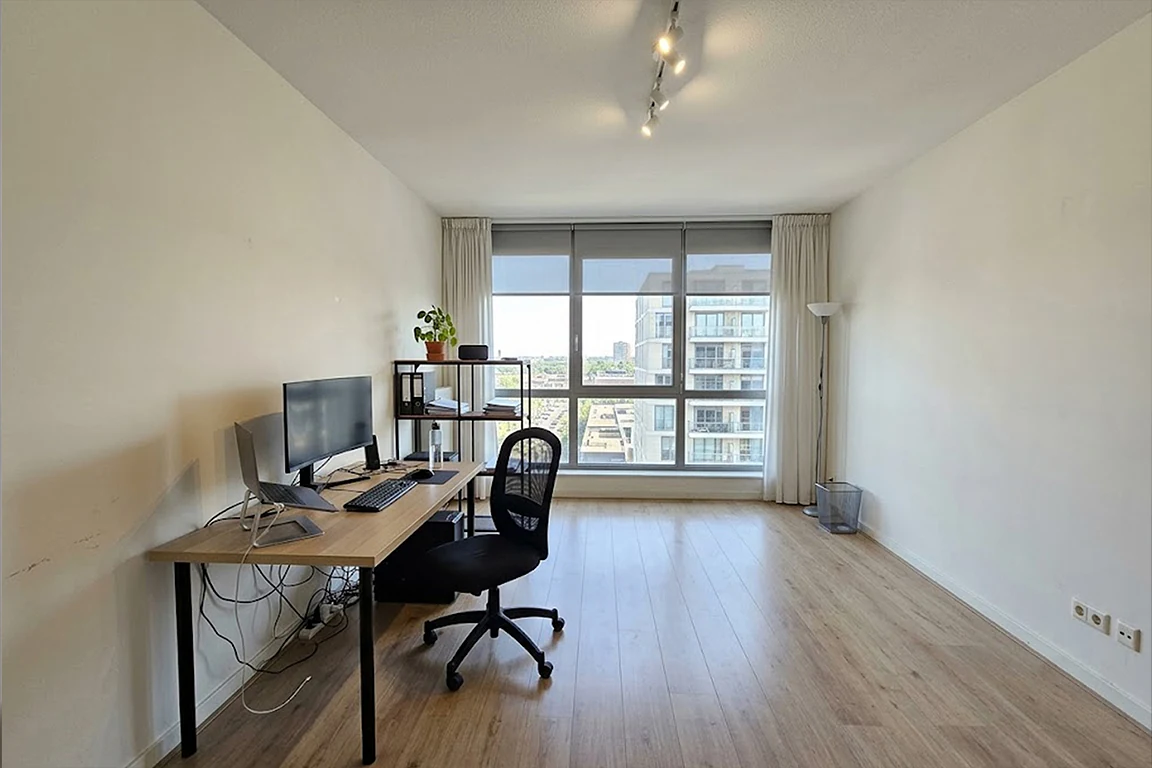 Basic home office before workspace mood transformation, with plain white walls, simple desk, visible cables, office chair, minimal furniture and large window with unused design potential.